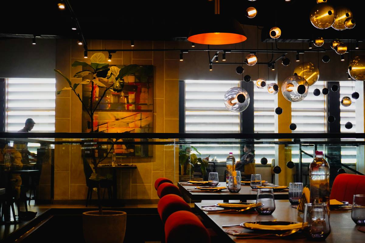 restaurant fine dining lighting showing layered ambient, accent, and task lighting over a linen-draped table with warm-toned pendant fixtures